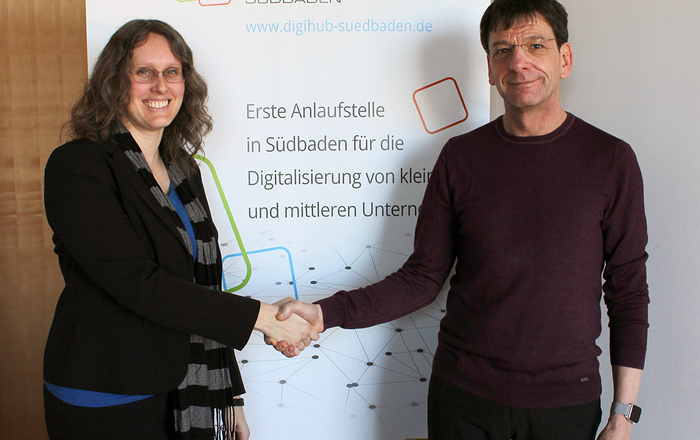 Prof. Dr. Gerhard Kachel (rechts) schüttelt Catharina Huf (links) vor eine DIGIHUB-Banner die Hand.