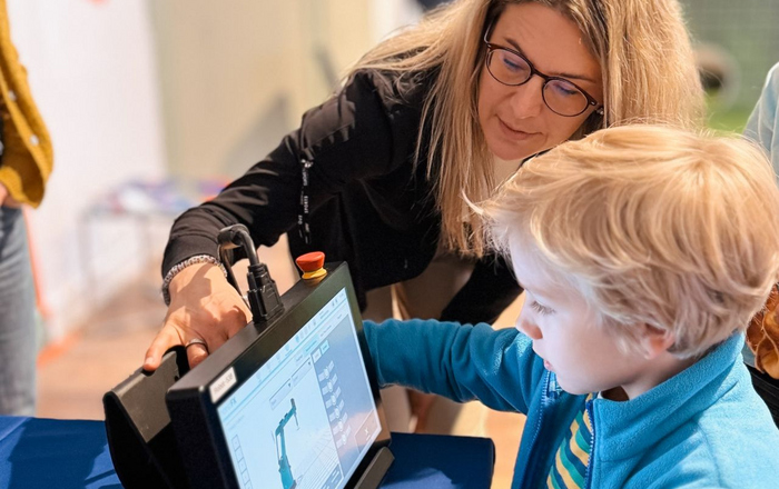 Eine Frau zeigt einem Jungen ein Tablet mit einem Roboter