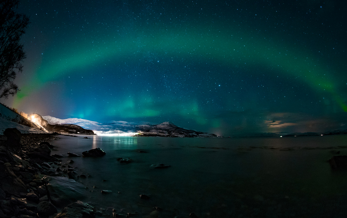 Lichtbogen über einer Bucht bei Nacht