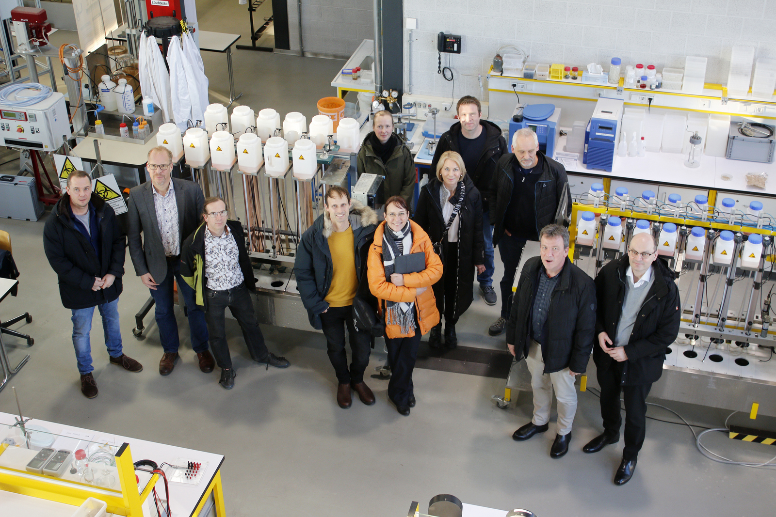 Gruppenbild der Kooperationspartnerinnen und -partner die im Technikum um eine Filteranlage herum stehen 