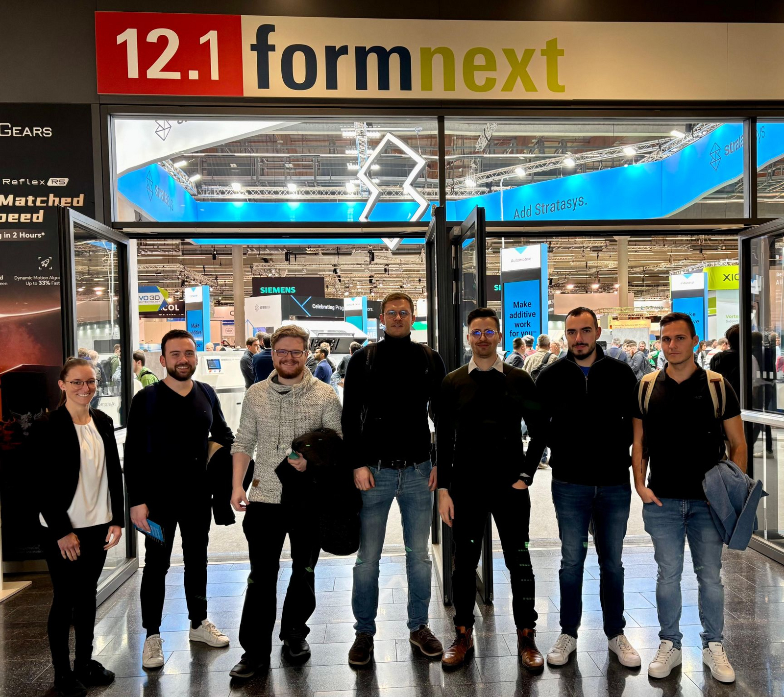 A group of people are standing in front of a sliding door with a sign that says 