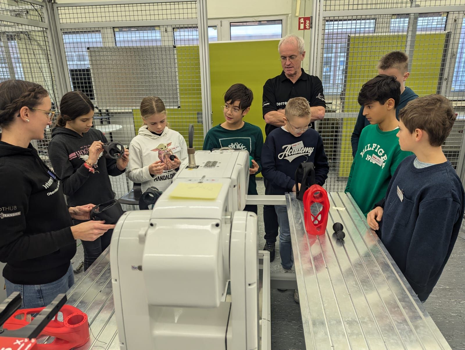 Ein Mann und eine Frau stehen mit einer Gruppe von Kindern um einen Roboter herum