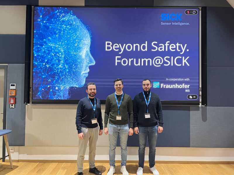  Drei Männer stehen vor einem Schild Beyond Safety Forum SICK