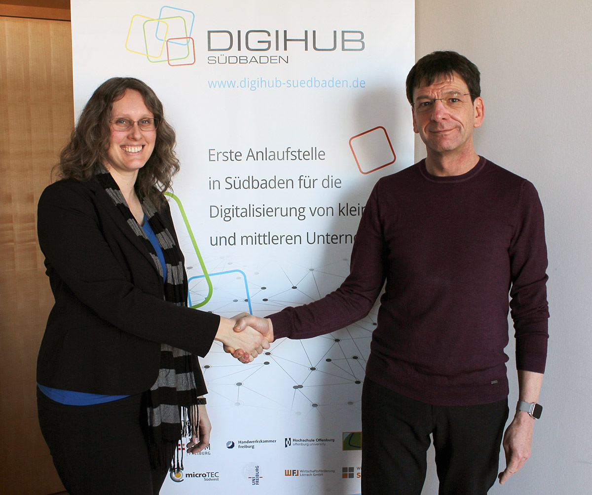 Prof. Dr. Gerhard Kachel (rechts) schüttelt Catharina Huf (links) vor eine DIGIHUB-Banner die Hand.